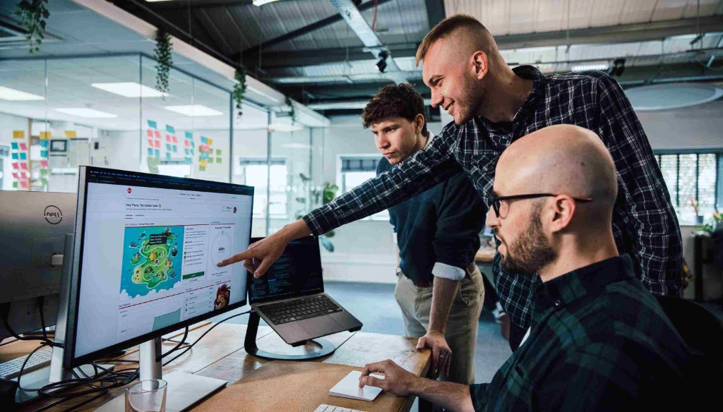 mmtm developers collaborating around a monitor and laptop in the office